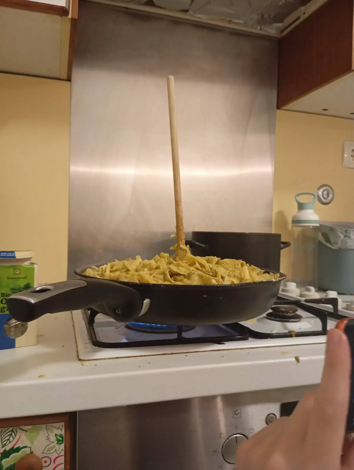 A spoon standing in a huge amount of pasta in a pan